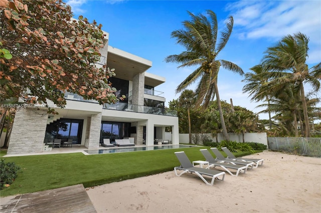 rear view of property featuring a balcony, a lawn, and a patio