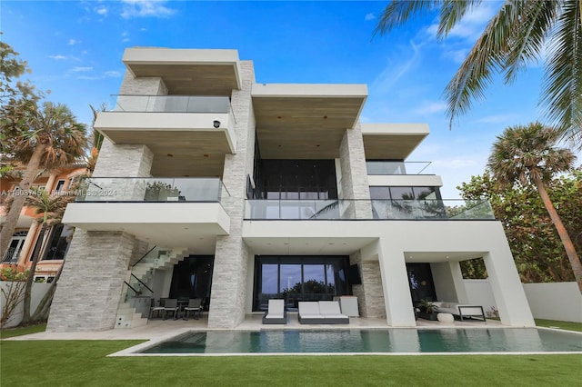 rear view of house with a balcony, a yard, and a patio