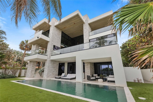 rear view of house featuring a balcony, a patio area, a fenced in pool, a yard, and an outdoor hangout area