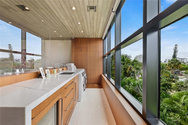 sunroom / solarium featuring wood ceiling, a healthy amount of sunlight, sink, and a water view