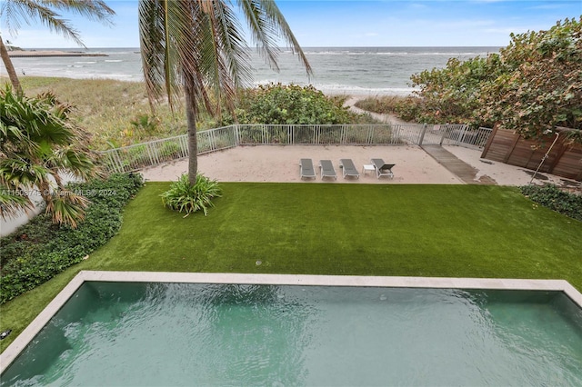 view of pool featuring a view of the beach, a yard, and a water view