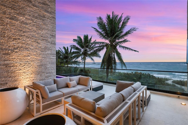 patio terrace at dusk with a water view, outdoor lounge area, and a balcony