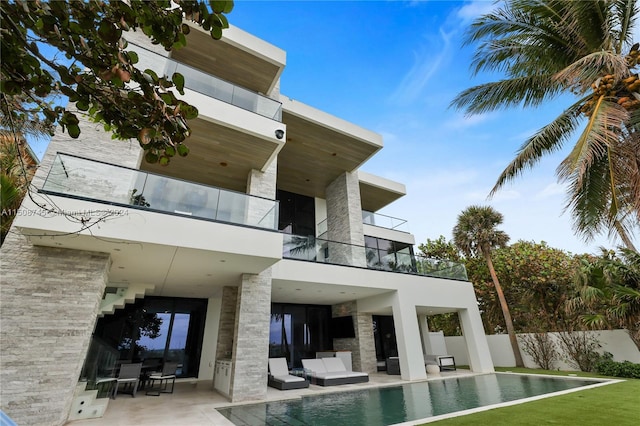 exterior space with a balcony, a fenced in pool, an outdoor hangout area, and a patio