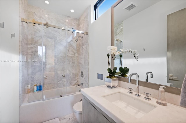 full bathroom with combined bath / shower with glass door, vanity, and toilet