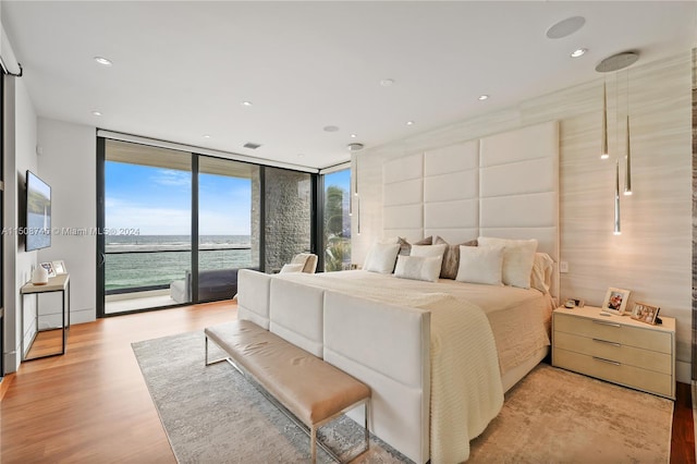 bedroom featuring light wood-type flooring, a wall of windows, and access to outside