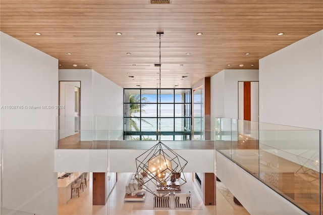 interior space with pendant lighting, expansive windows, a chandelier, and wooden ceiling