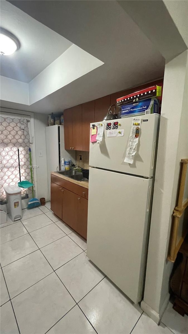 kitchen with light tile patterned floors, sink, and white refrigerator