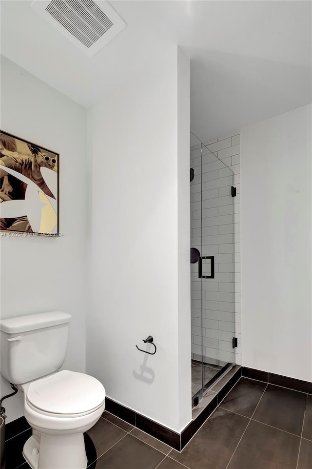 bathroom with toilet, a shower with shower door, and tile patterned flooring