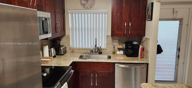 kitchen featuring tasteful backsplash, appliances with stainless steel finishes, light stone counters, and a sink