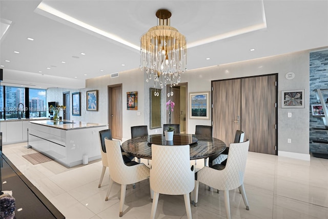 tiled dining room with sink, a raised ceiling, and an inviting chandelier