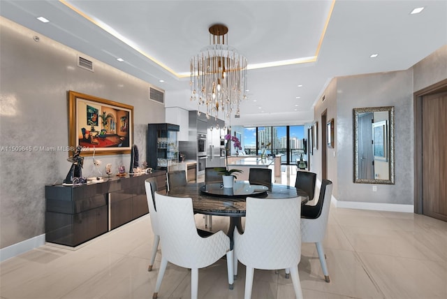 dining room featuring a chandelier, light tile flooring, and a raised ceiling