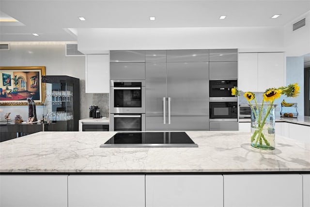 kitchen featuring appliances with stainless steel finishes, light stone countertops, tasteful backsplash, and a kitchen island