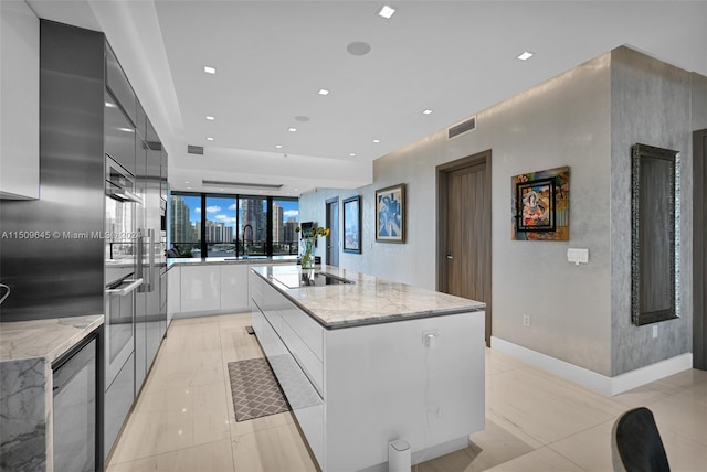 kitchen with an island with sink, sink, white cabinetry, and light tile floors