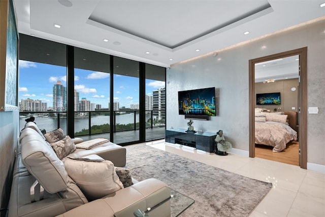 living room with tile floors, a raised ceiling, floor to ceiling windows, and a water view