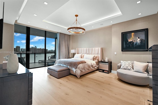 bedroom featuring floor to ceiling windows, wood-type flooring, a raised ceiling, and access to exterior