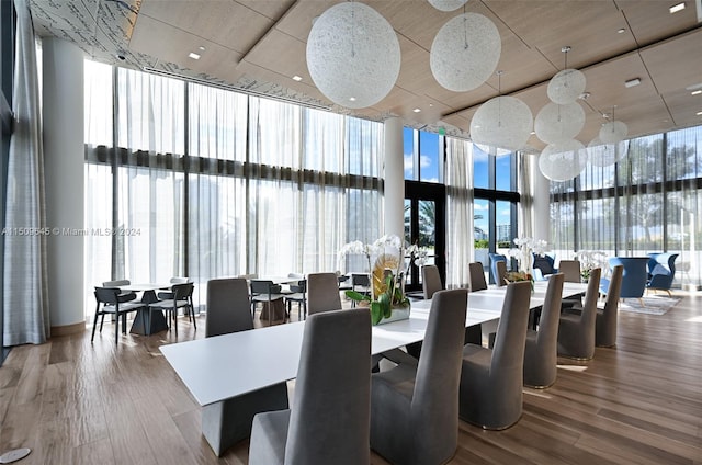 dining space with a towering ceiling, hardwood / wood-style floors, and a wall of windows