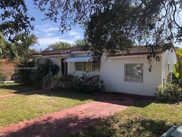 1256 NE 149th St, Miami, FL 33161 - mediterranean / spanish-style house with a front lawn, stucco siding, and a tile roof