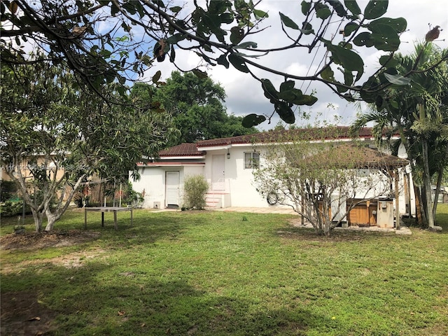 1256 NE 149th St, Miami, FL 33161 - rear view of house with stucco siding, a yard, and a tile roof