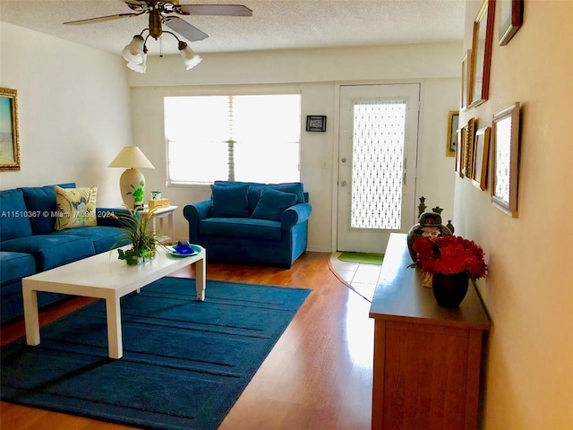 living room with plenty of natural light, a textured ceiling, ceiling fan, and light wood-type flooring