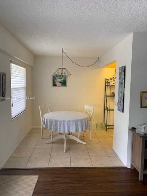 dining room featuring a textured ceiling, a notable chandelier, and light hardwood / wood-style flooring