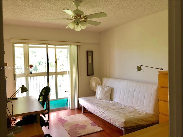 sitting room featuring hardwood / wood-style floors, ceiling fan, and a textured ceiling