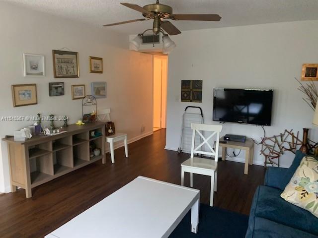 living room featuring ceiling fan and dark hardwood / wood-style flooring