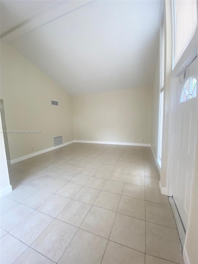 tiled empty room featuring lofted ceiling