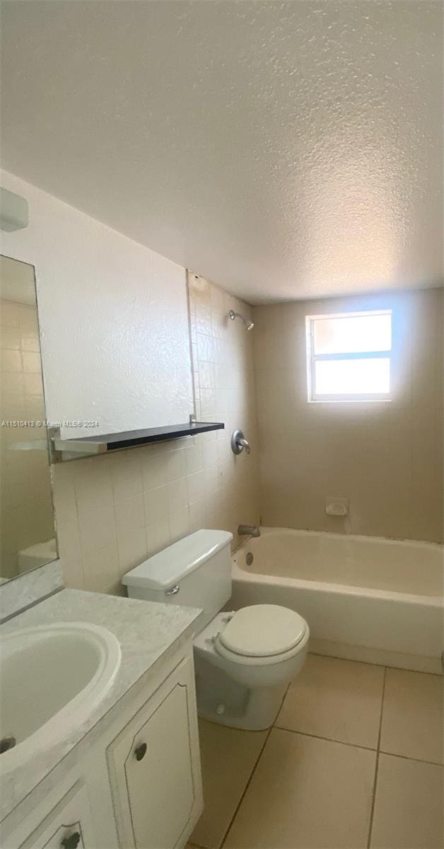 full bathroom featuring a textured ceiling, tile walls, tiled shower / bath combo, vanity, and toilet