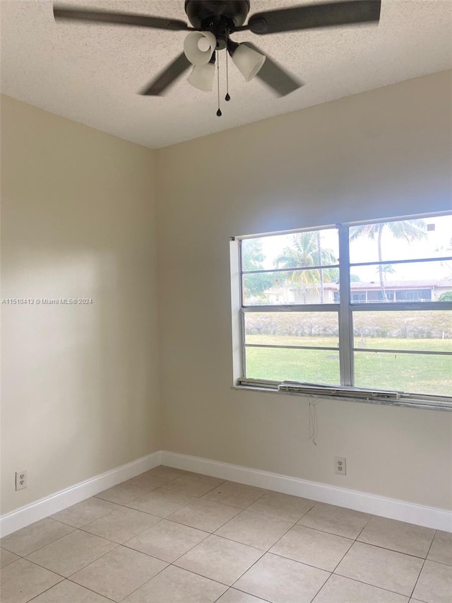 unfurnished room with a textured ceiling, ceiling fan, and light tile flooring