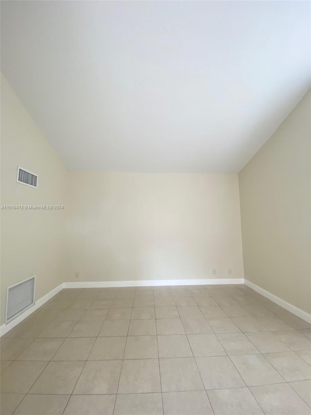 spare room featuring lofted ceiling and light tile floors