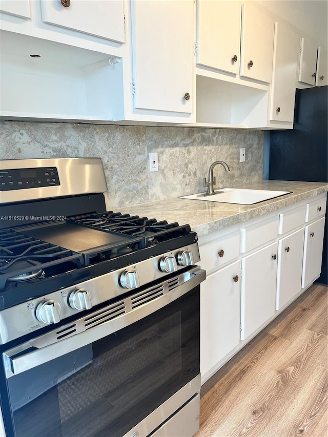 kitchen with gas stove, white cabinetry, and light hardwood / wood-style flooring