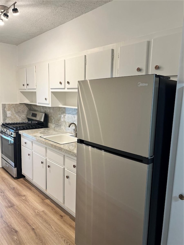 55 NW 204th St Unit 20, Miami Gardens, FL 33169 - kitchen with decorative backsplash, appliances with stainless steel finishes, white cabinetry, a sink, and light wood-style floors