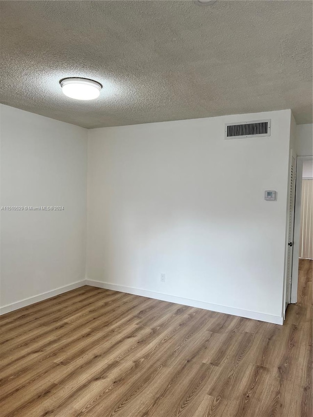 empty room with a textured ceiling and wood-type flooring