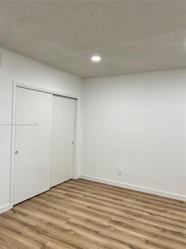 unfurnished bedroom with a textured ceiling, light hardwood / wood-style flooring, and a closet