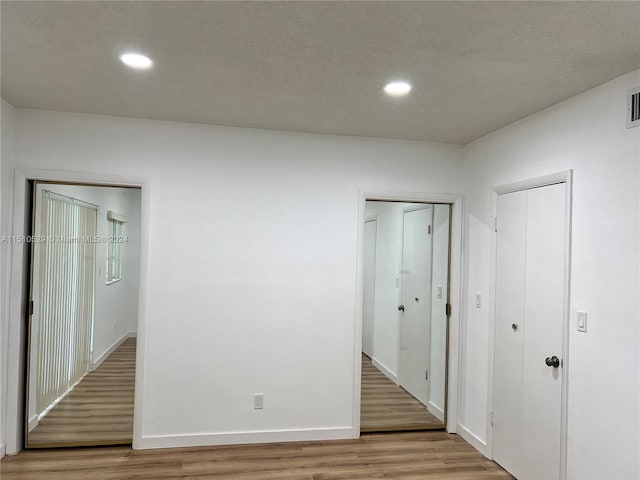 spare room featuring wood-type flooring and a textured ceiling