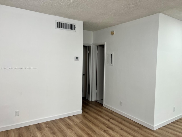 empty room featuring a textured ceiling and wood-type flooring