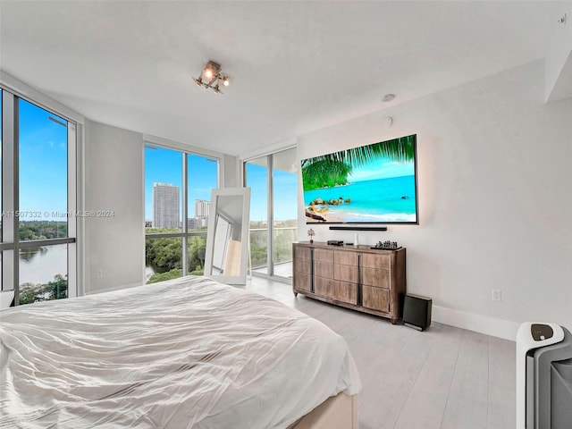 bedroom featuring light hardwood / wood-style flooring, expansive windows, and access to outside