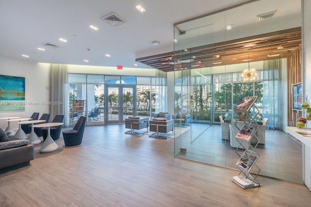 exercise room featuring floor to ceiling windows, wood-type flooring, a notable chandelier, and french doors