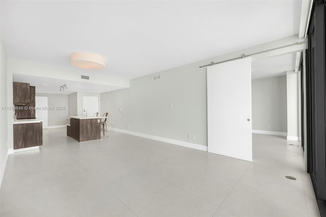 unfurnished living room featuring a barn door and light tile patterned floors