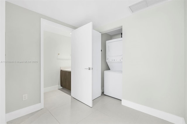 laundry area with stacked washing maching and dryer and light tile patterned floors