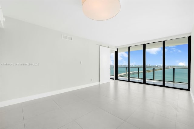 unfurnished room with expansive windows and a water view