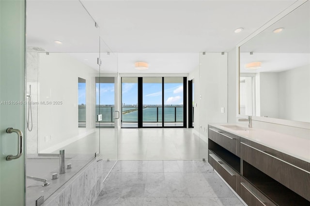 bathroom featuring a wall of windows, a shower with shower door, vanity, and a water view