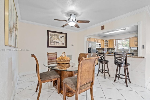 tiled dining space featuring ornamental molding and ceiling fan