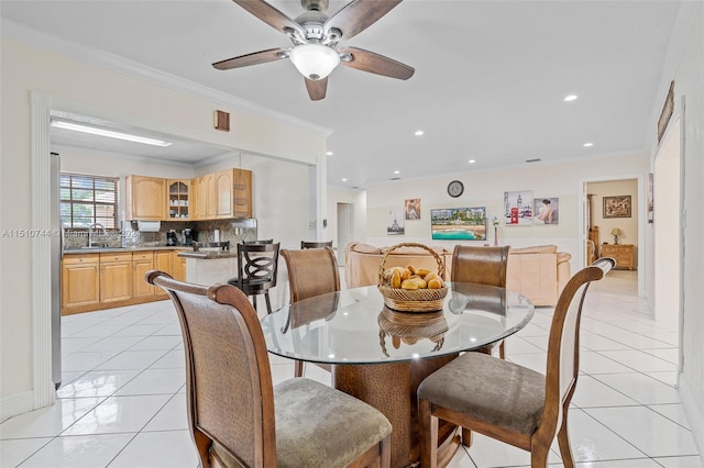 tiled dining room with ornamental molding, sink, and ceiling fan