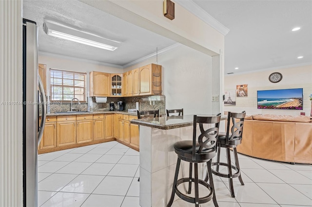 kitchen featuring a breakfast bar, sink, kitchen peninsula, backsplash, and light tile patterned floors