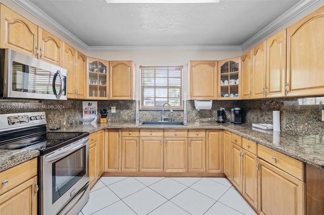 kitchen with sink, light tile patterned floors, dark stone counters, and stainless steel appliances