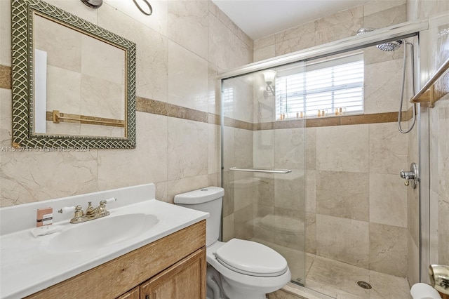 bathroom with a shower with door, vanity, tile walls, and toilet