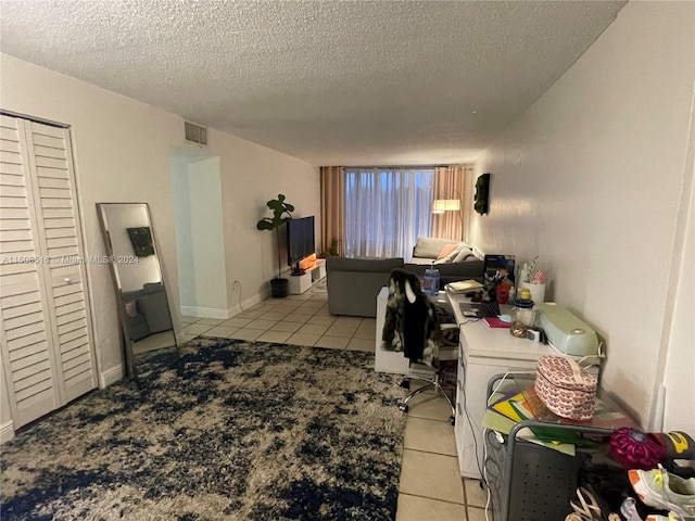 office space with light tile flooring, washer / clothes dryer, and a textured ceiling