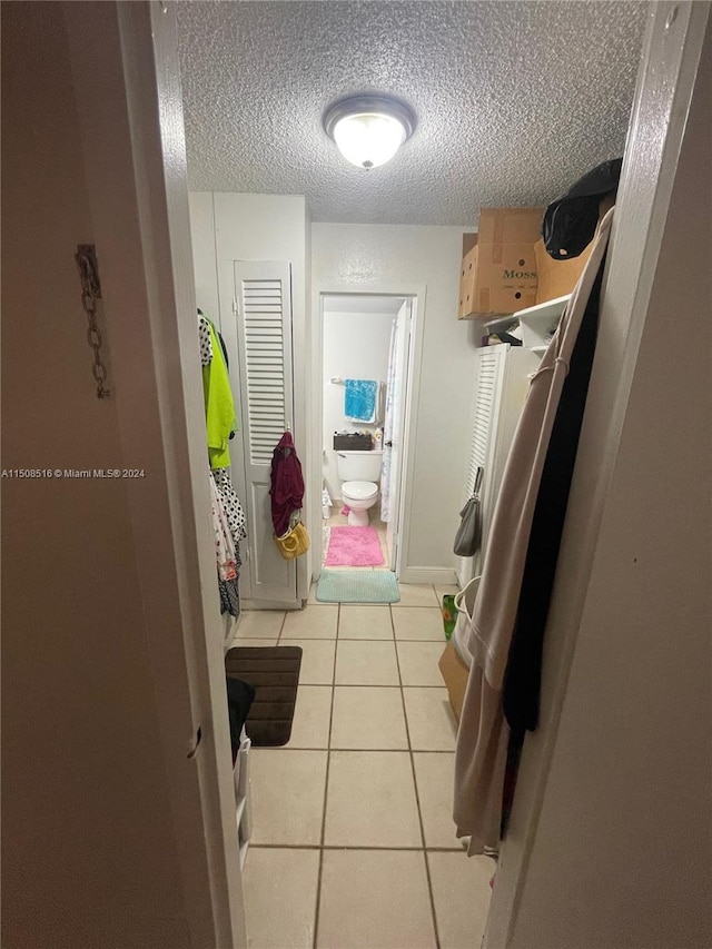 hallway with light tile floors and a textured ceiling