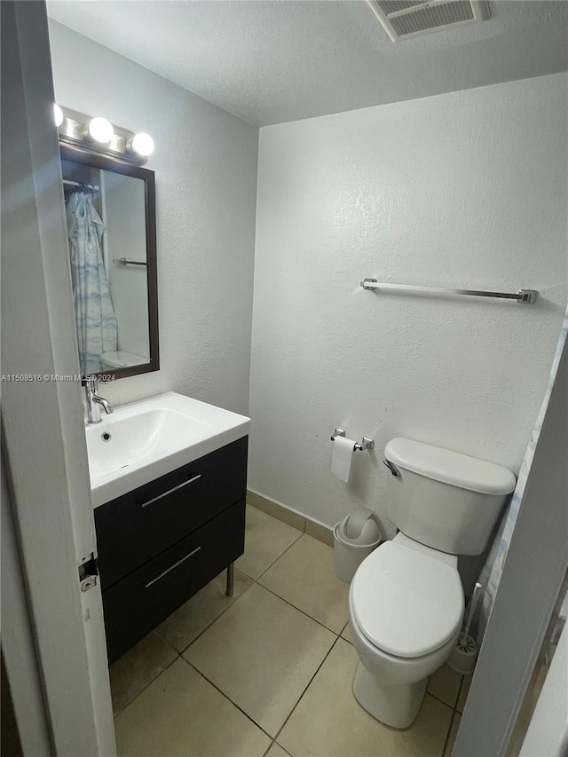 bathroom featuring toilet, a textured ceiling, tile floors, and large vanity